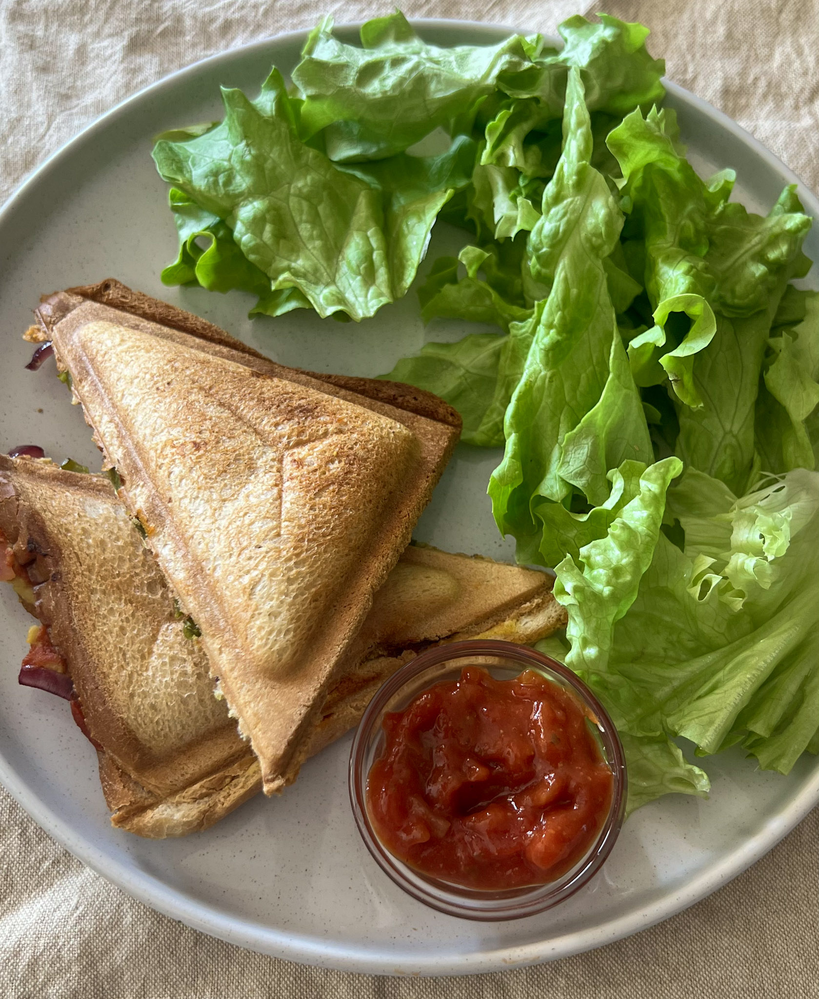 Beans Masala Sandwich served on a white plate with ketchup and lettuce on the side