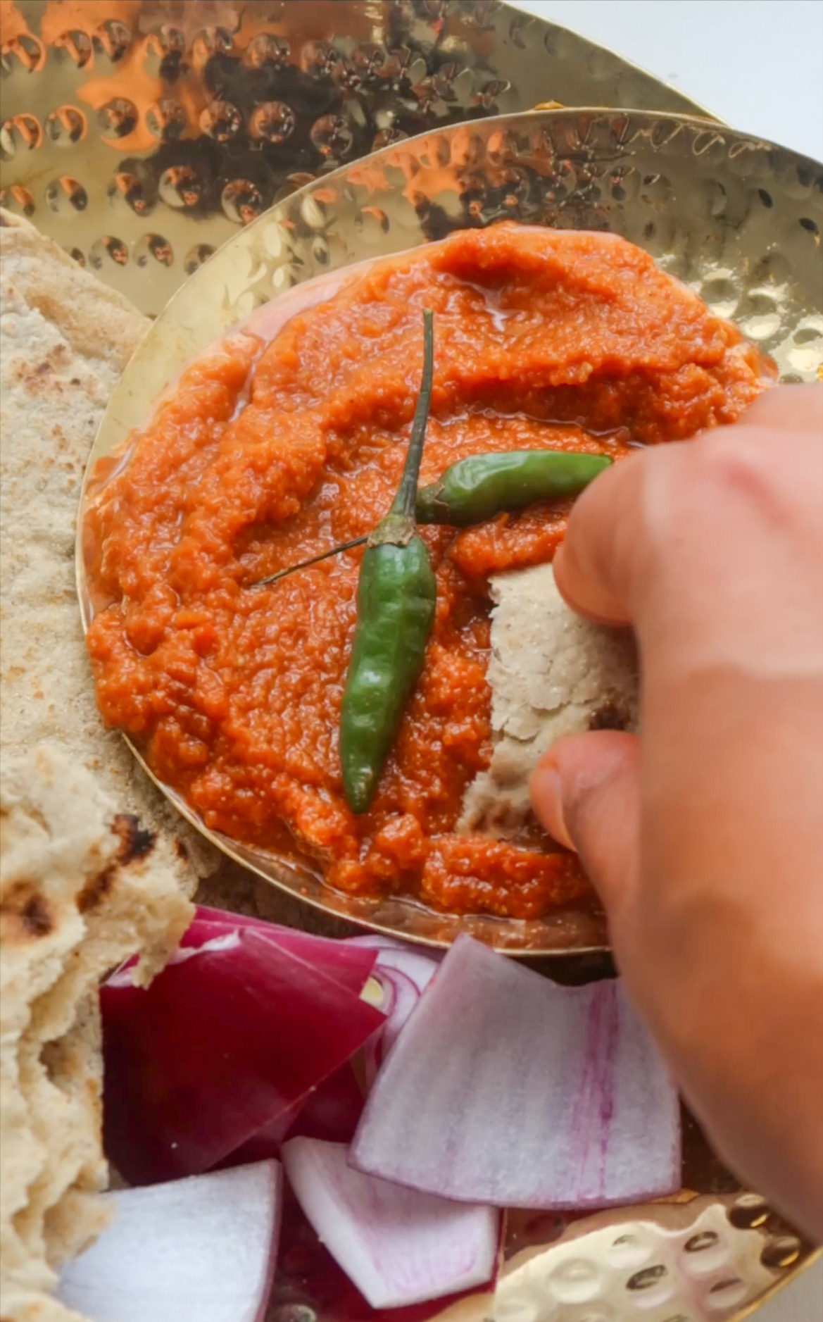 Scooping up lahsun chutney with a piece of Bajra roti