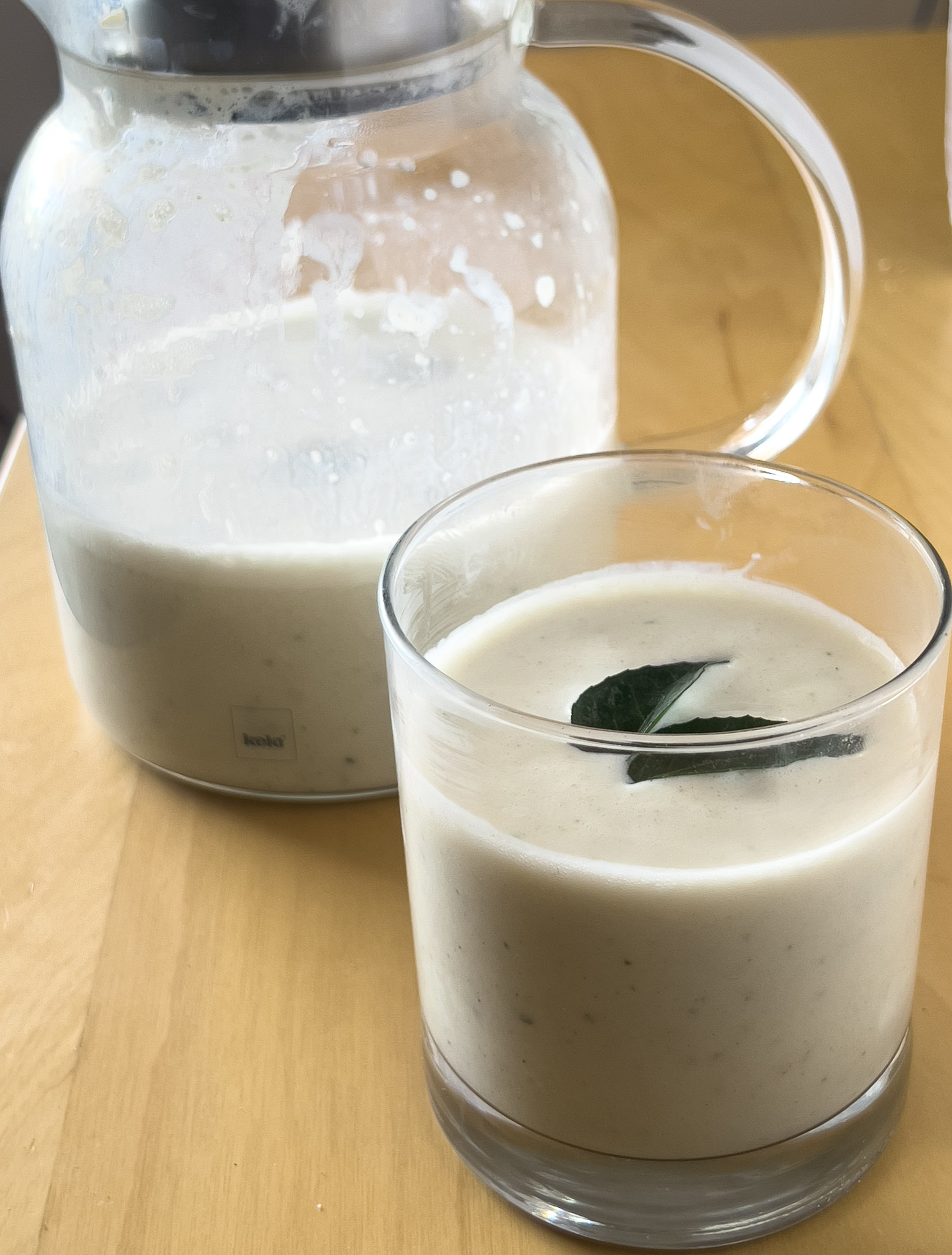 Vegan chaas served in a glass, garnished with curry leaves