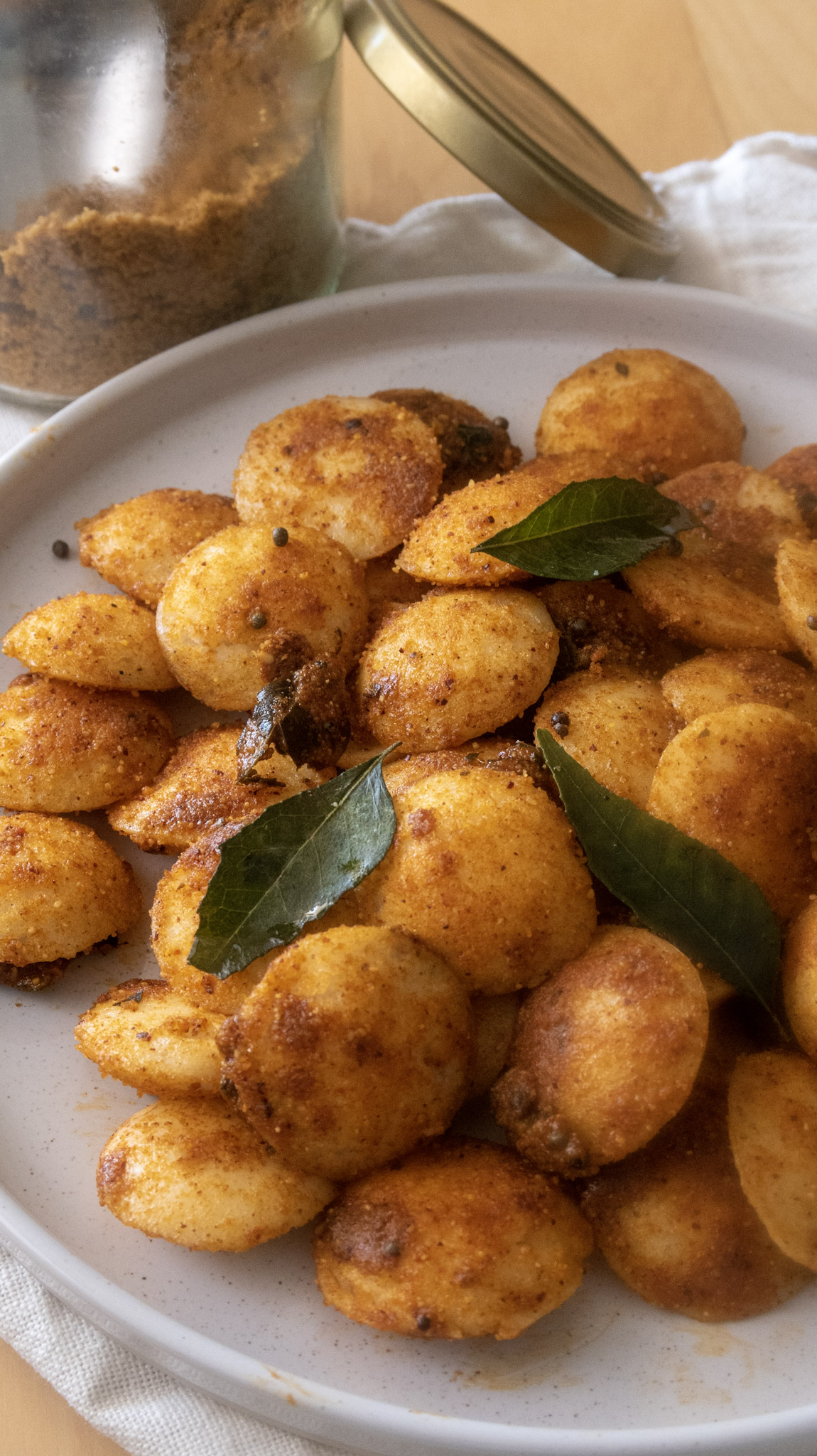 Mini podi idli served on a plate with a jar of idli podi on the side, front shot