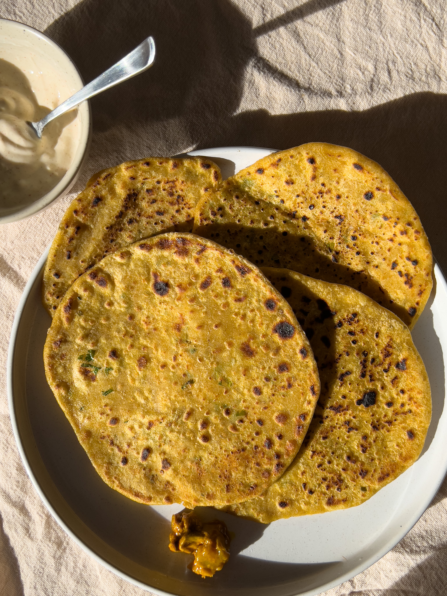 Mooli Paratha served with mango pickle and raita placed on a plate