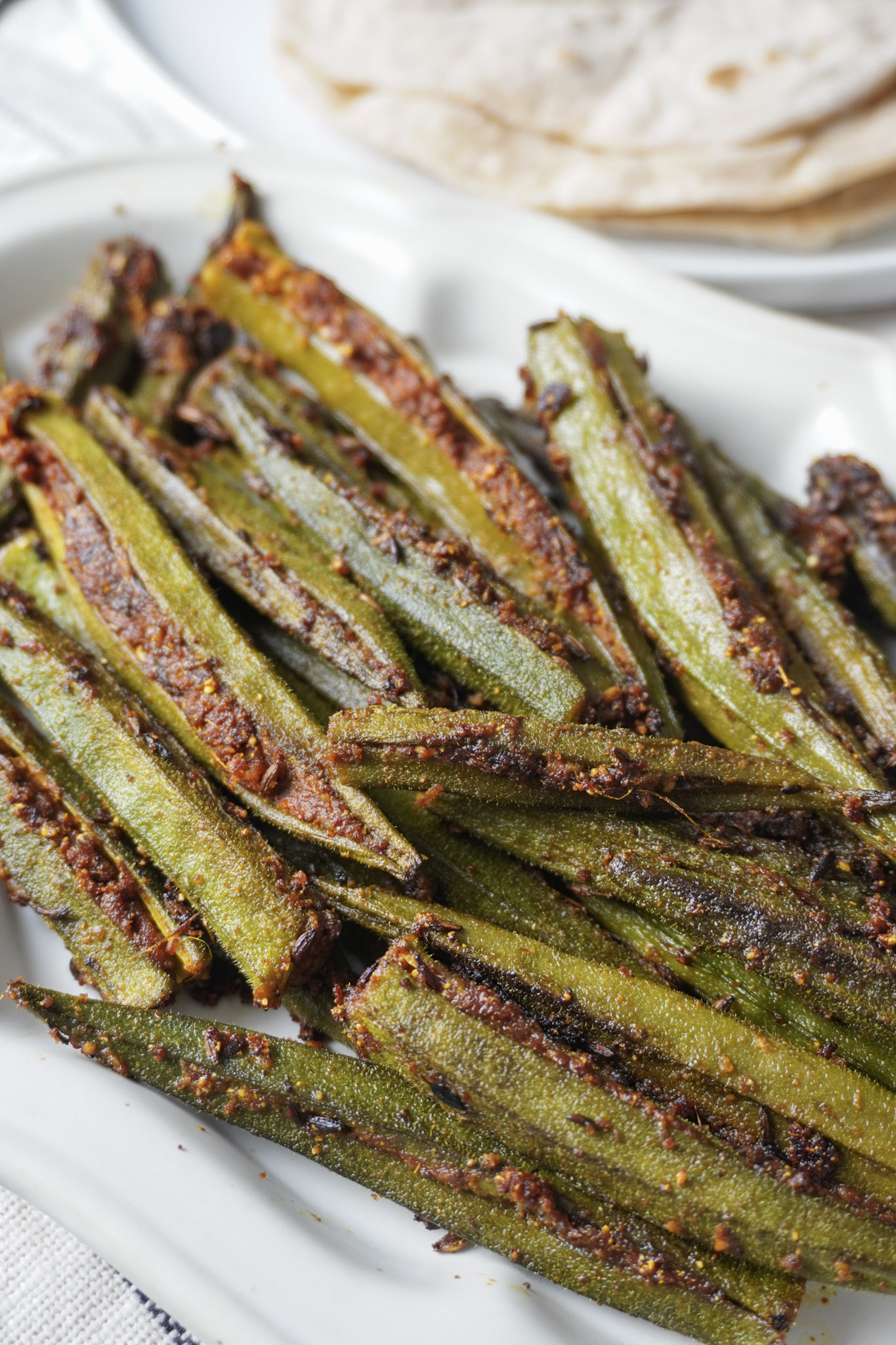 Bharwan Bhindi, stuffed bhindi, served on a white plate, side view, close-up shot