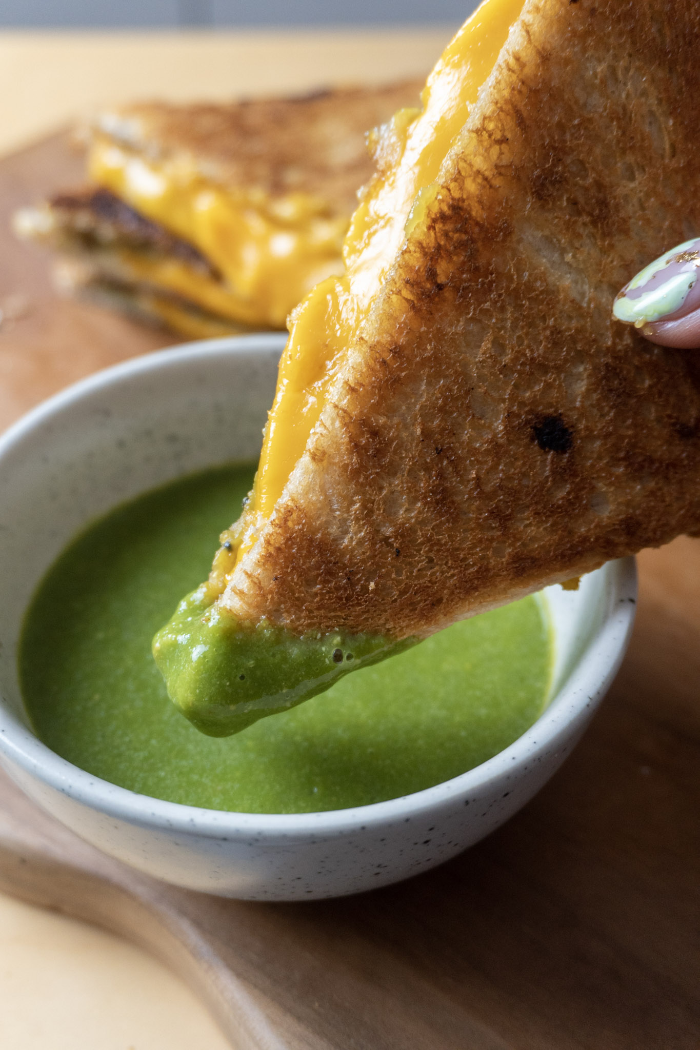 Vegan grilled cheese sandwich with caramelized onions, sliced in triangles, dipped in mint coriander chutney