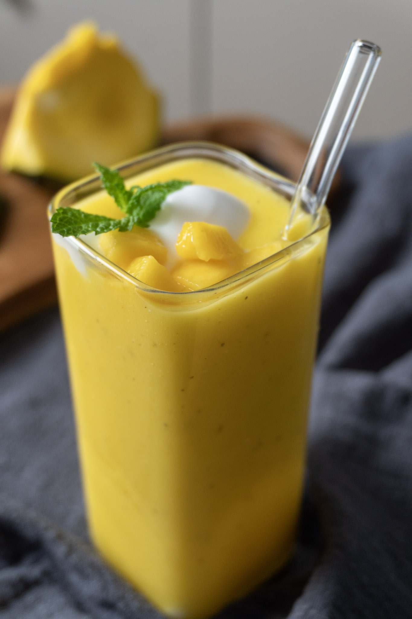 Vegan mango lassi in a tall glass with a straw.