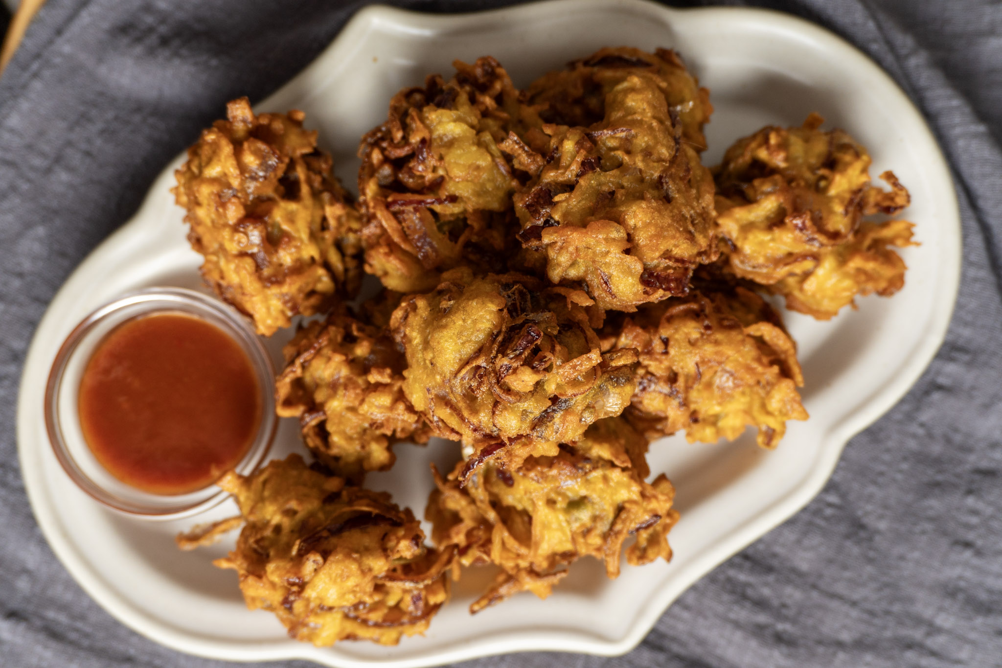 Onion potato bhajis served on a white long plate with ketchup on the side