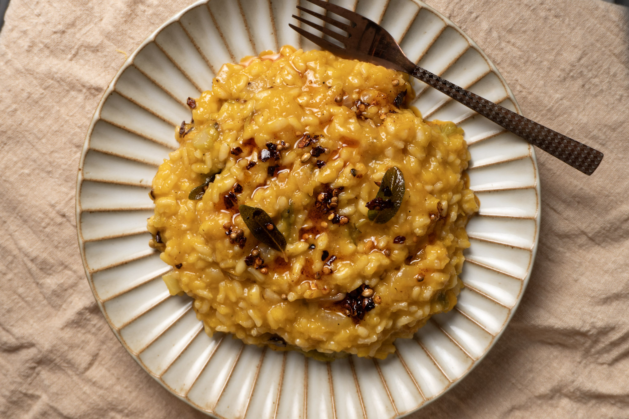 Butternut squash risotto served on a textured plate, top shot.