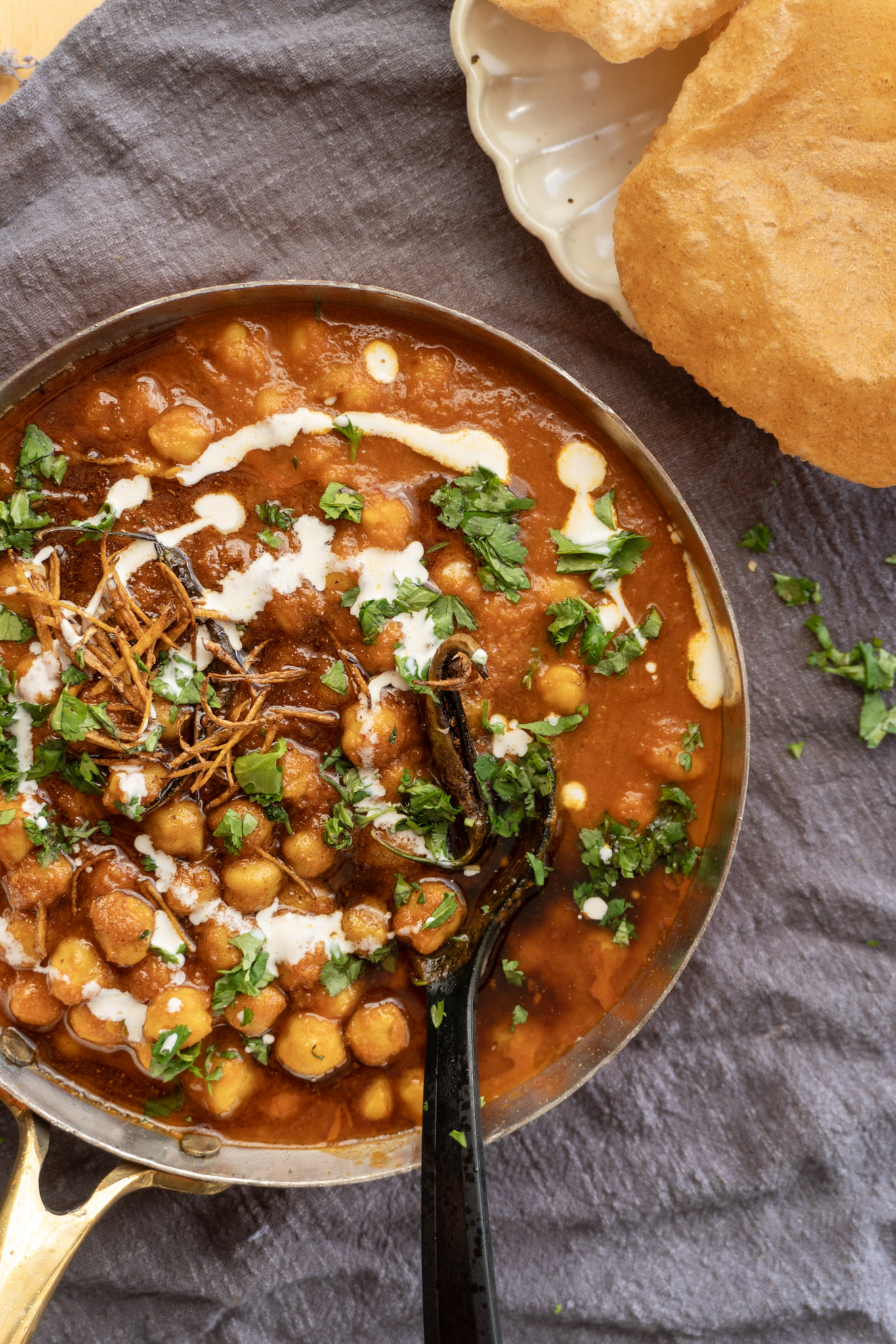 Top view of chana masal in a pan, garnished with corriander and plant-based cream