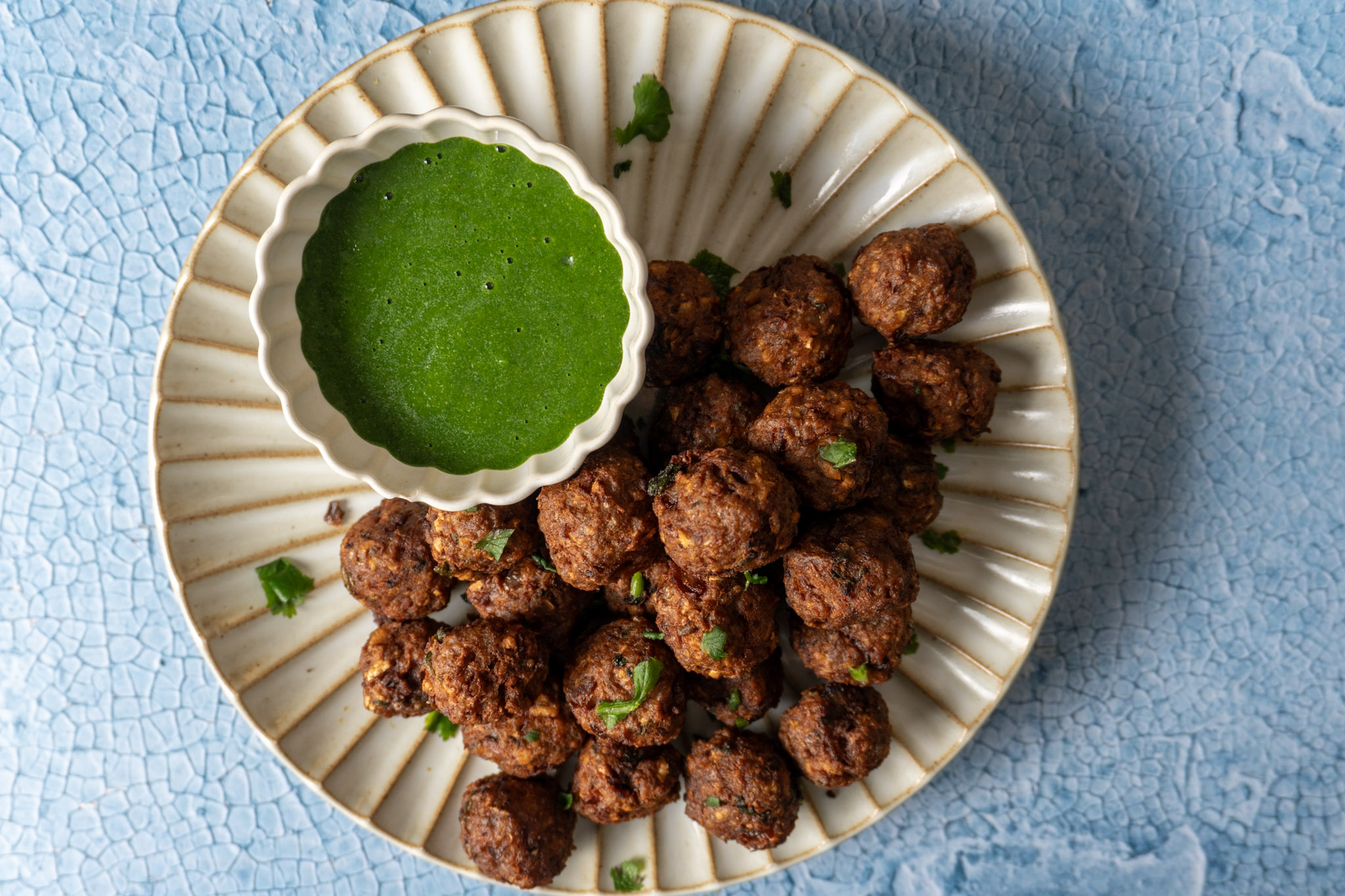 Vegan meatballs and chutney served on a white plate and bowl, top views.