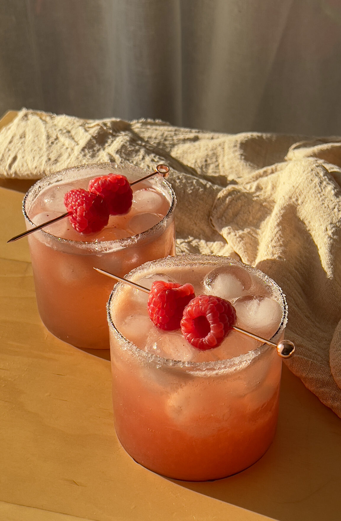 Two raspberry ginger rosemary mocktail drinks sitting in the sun.