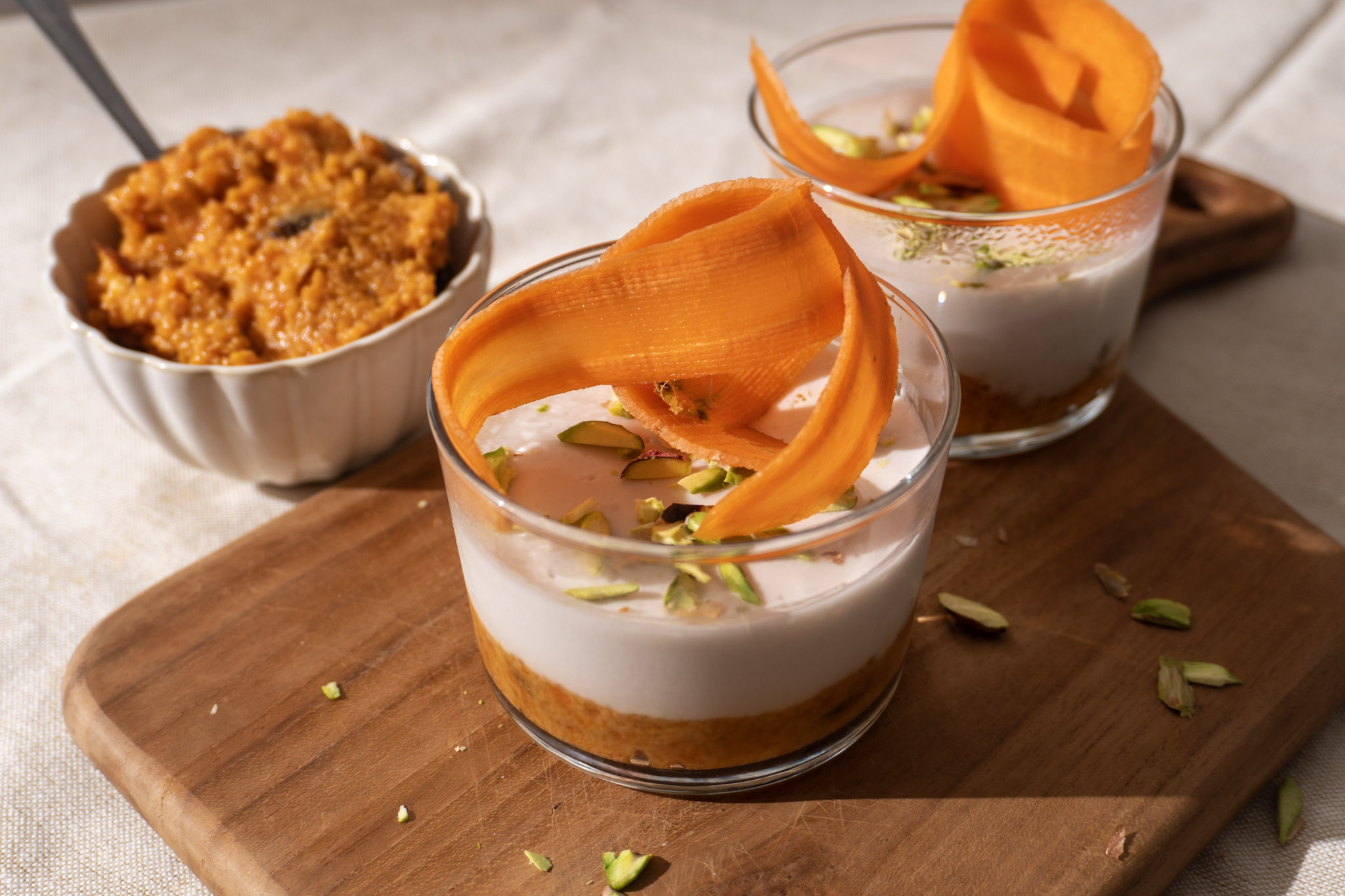 Vegan carrot halwa Panna Cotta in 2 cups, garnished with pistachios, landscape view.