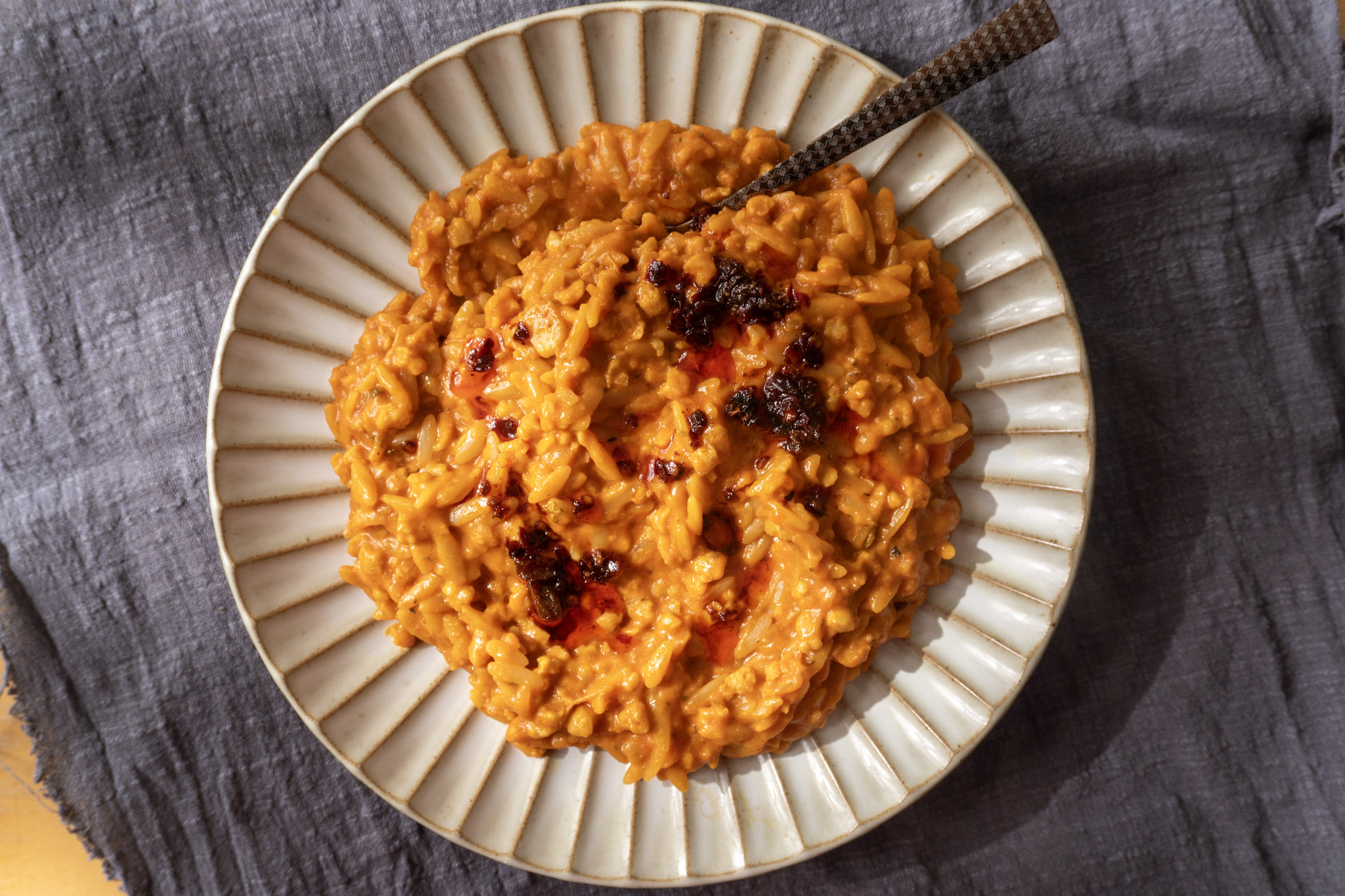 Spicy Gochujang Orzo in a white plate, with chili oil on top.