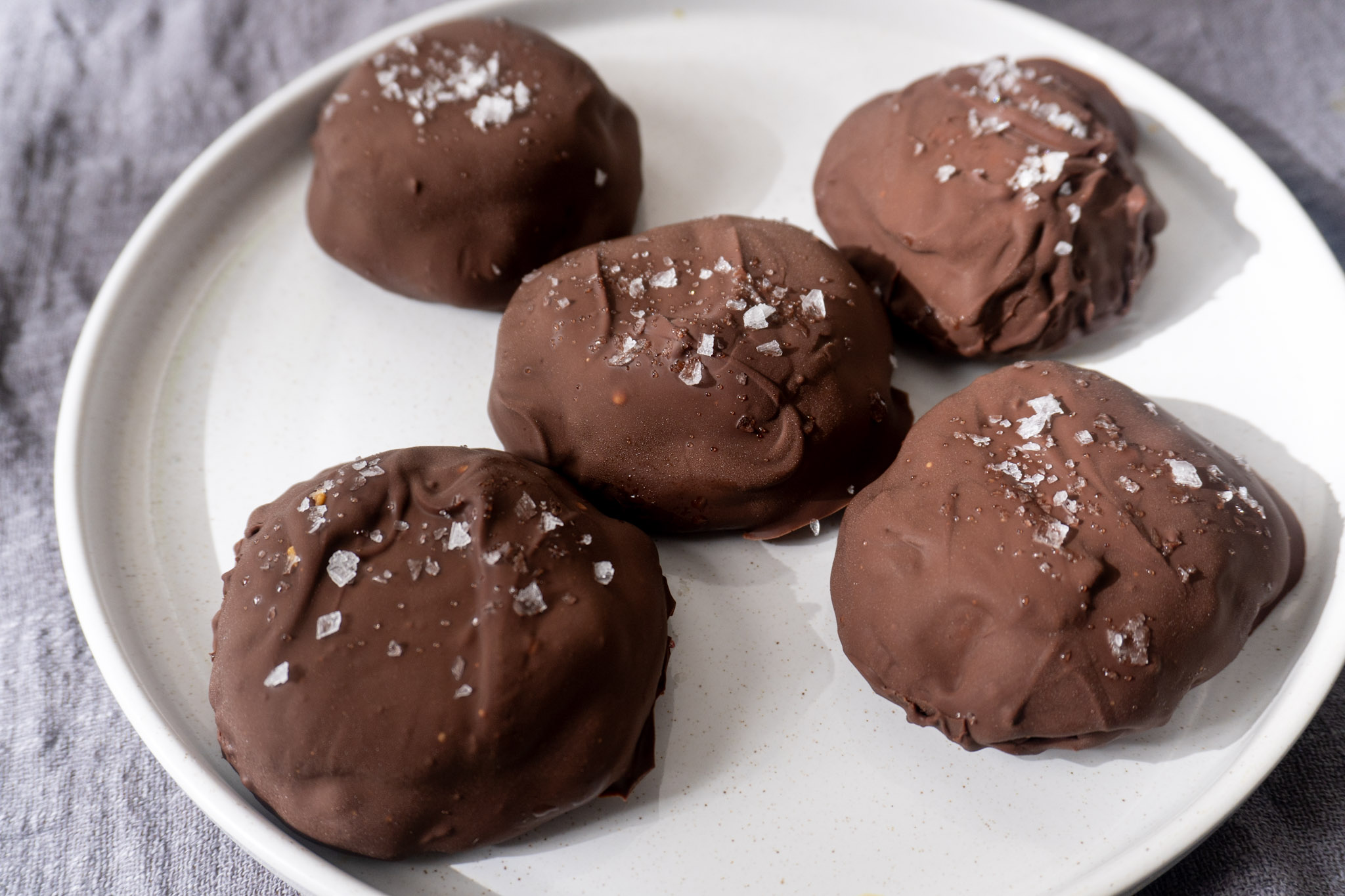 Dark chocolate peanut butter raspberry bites layer out on a white plate