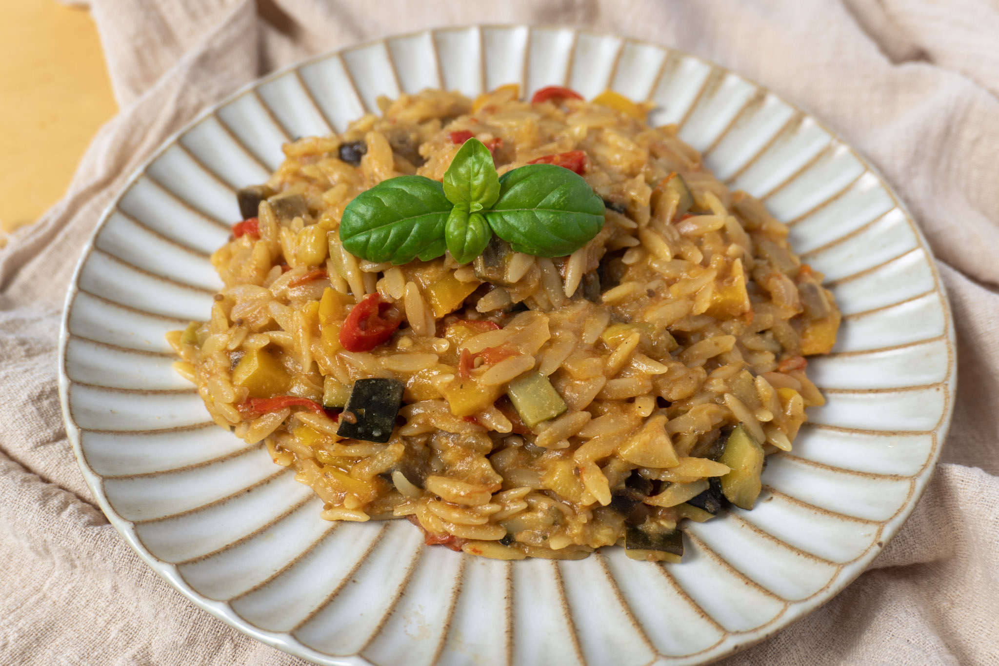 one pot healthy vegetable orzo dish served on a white plate. Front angle, landscape view.