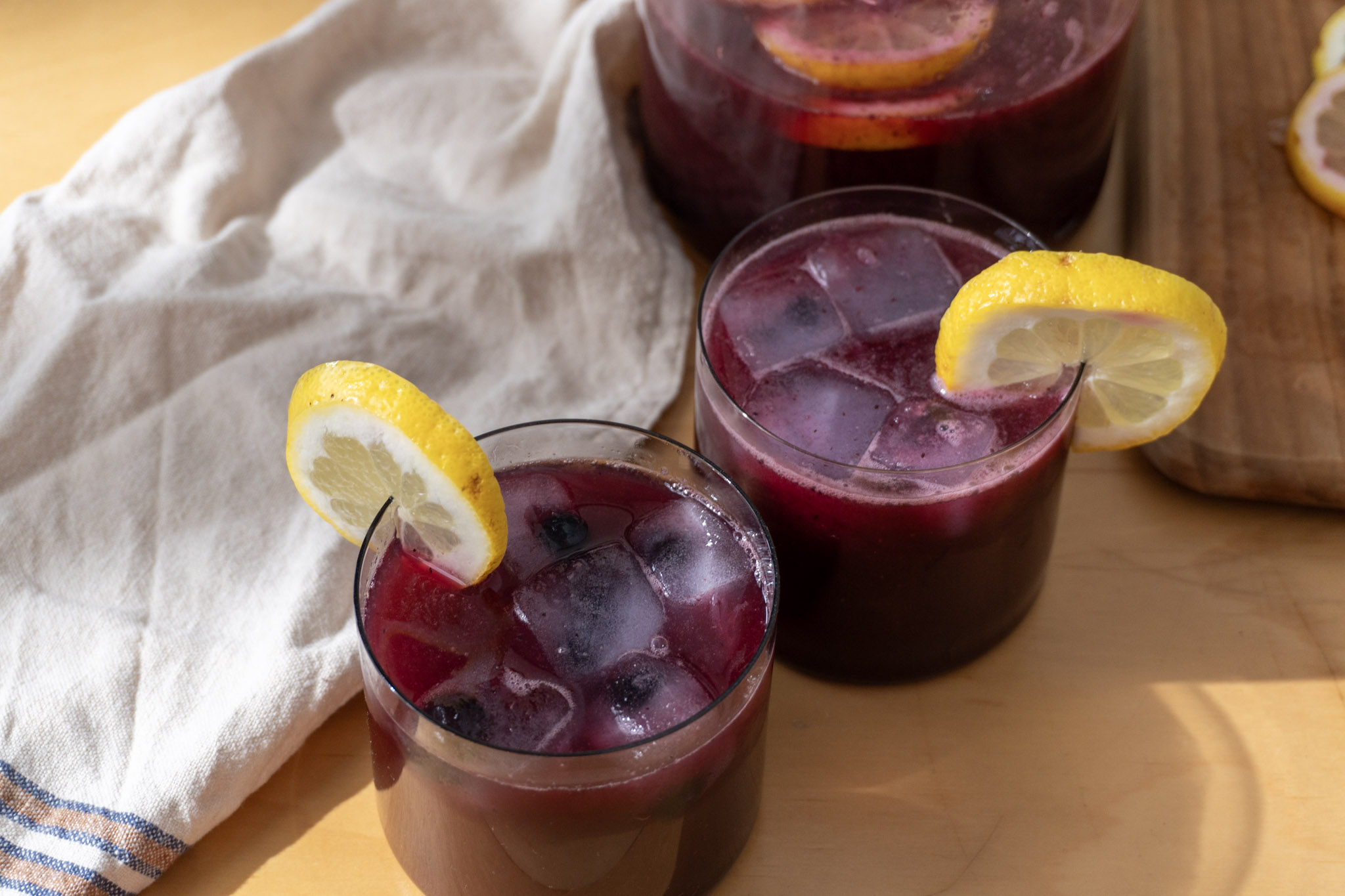 blueberry lemonade served in two glasses garnished with lemon slices