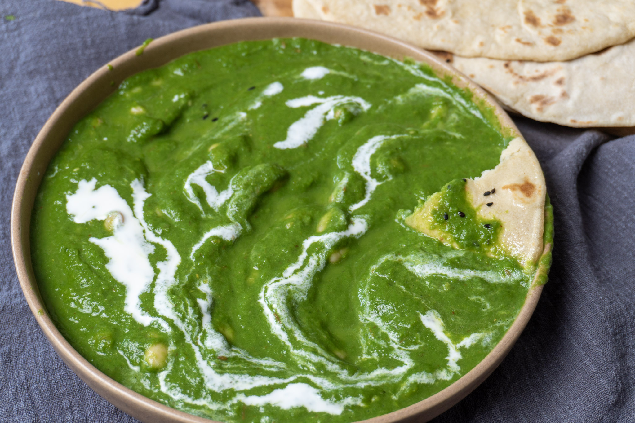 white beans Swiss chard saag in a wide bowl with naan on the side.