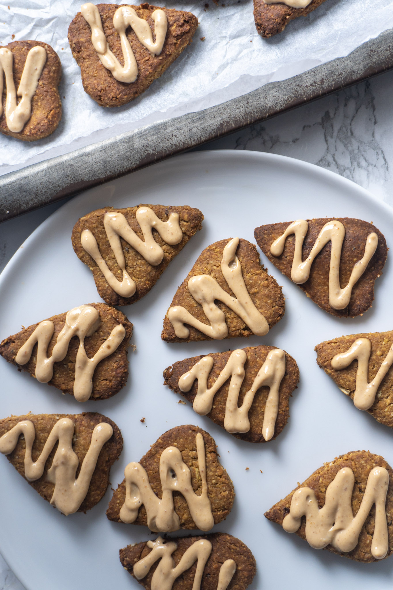 Peanut butter oat dog cookie treats on a white plate. Top view.