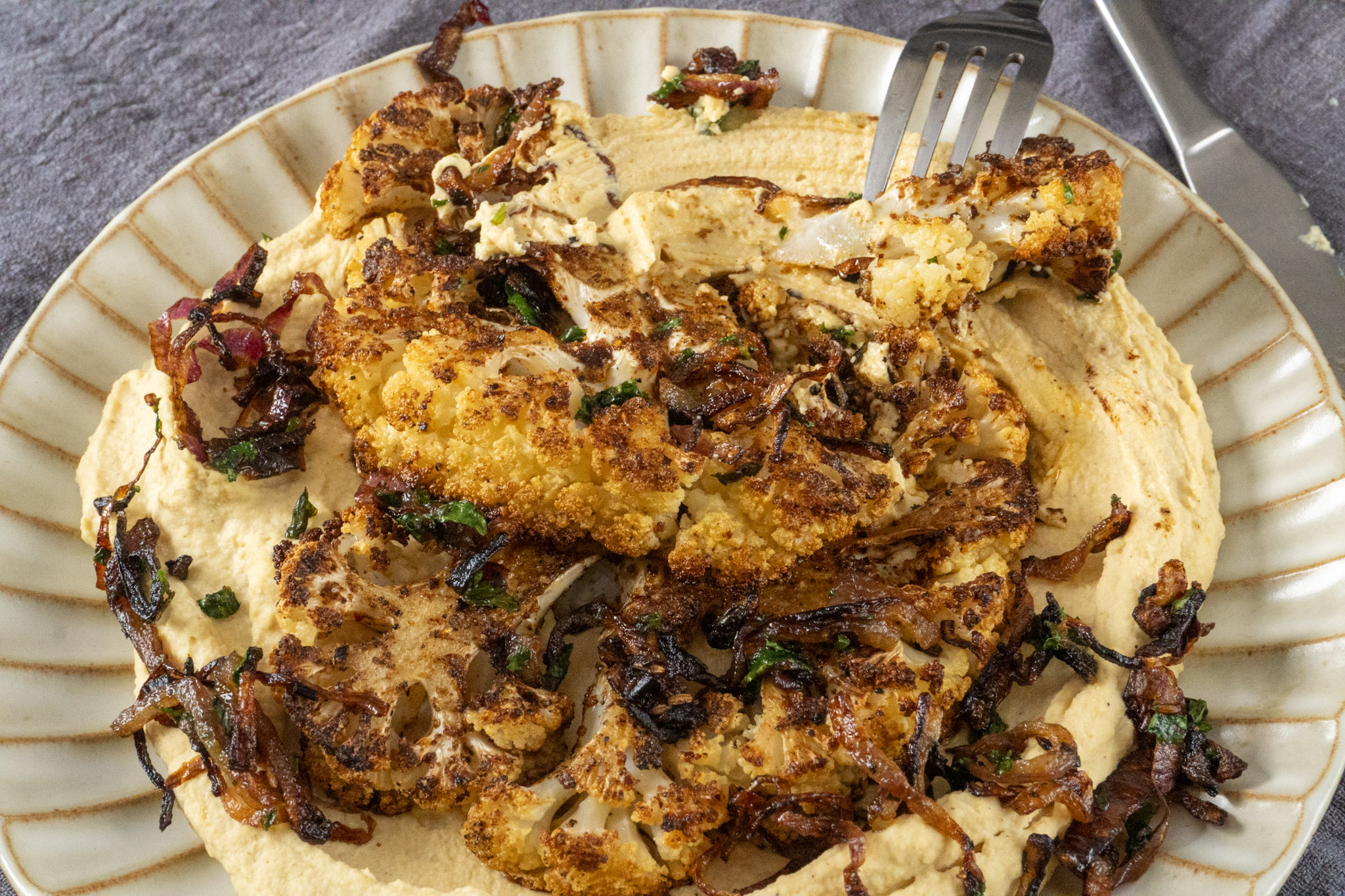 Roasted Cauliflower Steak served on a plate with hummus
