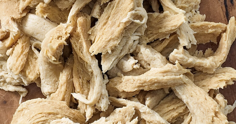 Shreddable vegan chicken (homemade seitan) on a cutting board, top shot, close up