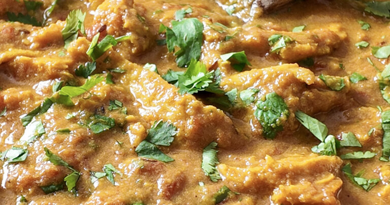 seitan chicken curry on the pot, with a wooden spoon in the pan