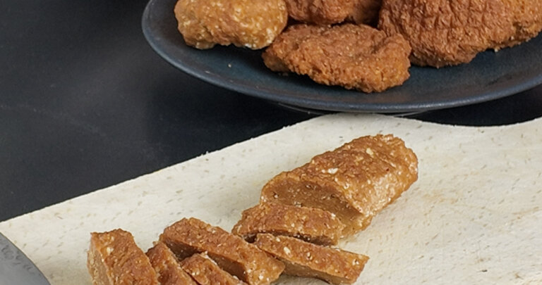 Spicy seitan sausage cut to pieces on a wooden chopping board