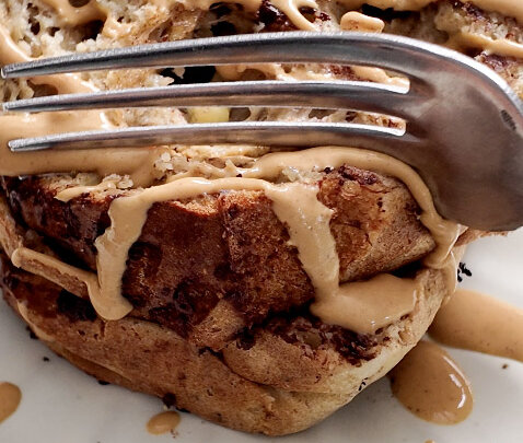 High protein banana bread on a plate, drizzled with peanut butter and a forkful taken out
